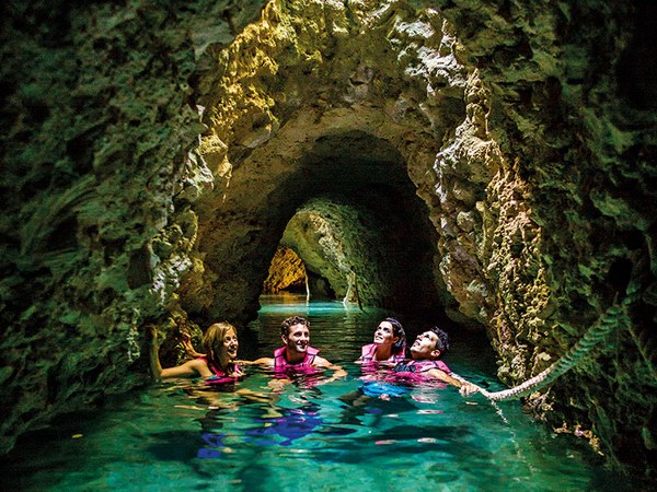 Visitors in life jackets floating through a cave on an underground river
