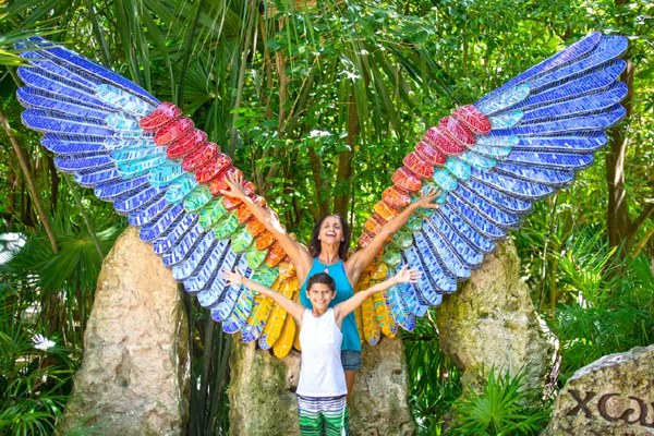 Child and adult posing between painted wings in a tropical garden
