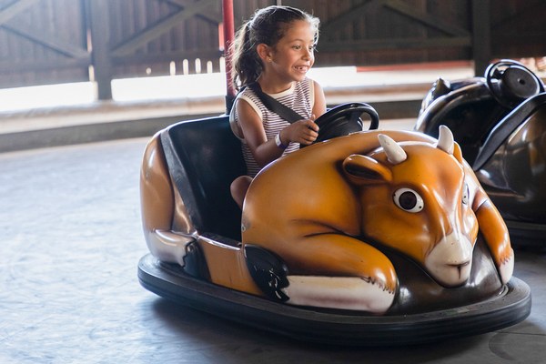 Niña conduciendo un coche con forma de león en la atracción Jabato
