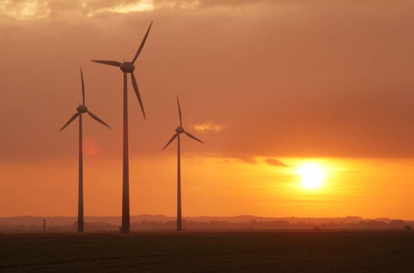Wind turbines silhouetted against an orange sunset sky, from the Ecotricity website