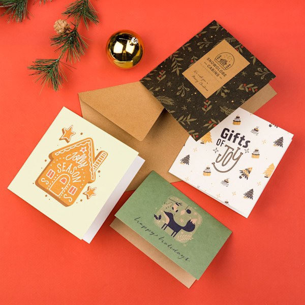 Verschillende gedrukte kerstkaarten met illustraties en kraft envelop op een rode achtergrond