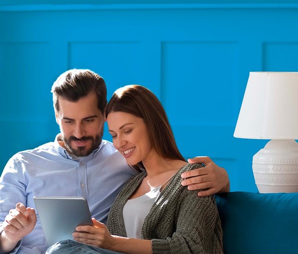 Coppia sul divano che controlla le offerte luce e gas su un tablet