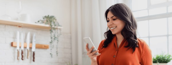 Woman smiling at her smartphone in a bright kitchen, from Superloop Bundle and Save