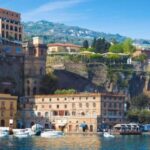 Porto di Sorrento con la scogliera e gli edifici che si affacciano sul mare, immagine di Ferryhopper