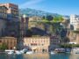 Porto di Sorrento con la scogliera e gli edifici che si affacciano sul mare, immagine di Ferryhopper