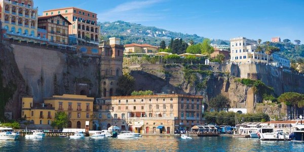 Porto di Sorrento con la scogliera e gli edifici che si affacciano sul mare, immagine di Ferryhopper