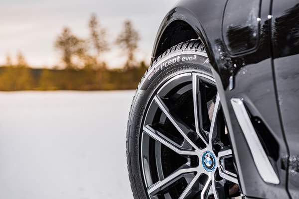 Winterreifen auf einer Alufelge an einem Auto in verschneiter Landschaft