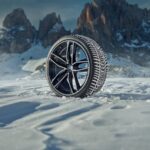 Winter-Komplettrad mit Alufelge im Schnee vor einer Bergkulisse