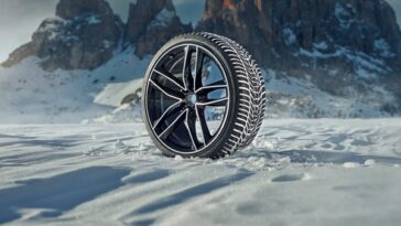Winter-Komplettrad mit Alufelge im Schnee vor einer Bergkulisse
