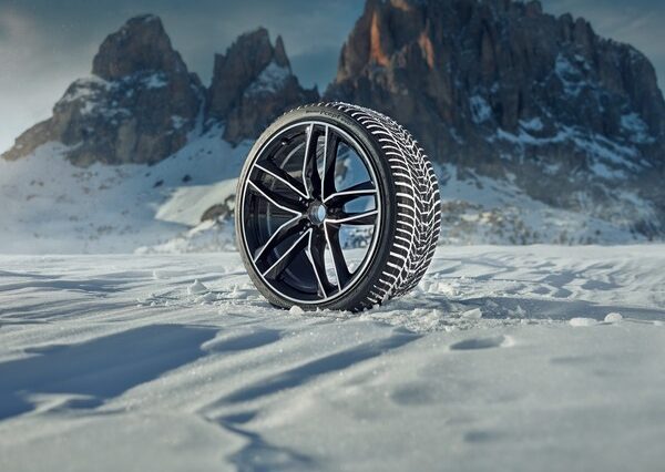 Winter-Komplettrad mit Alufelge im Schnee vor einer Bergkulisse