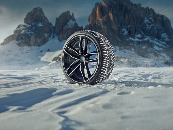 Winter-Komplettrad mit Alufelge im Schnee vor einer Bergkulisse